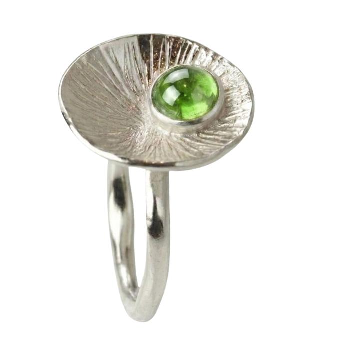 Handgefertigter Damenring aus Silber mit grünem facettiertem Peridot in runder Fassung auf strukturierter Scheibe und gehämmerter Ringschiene.